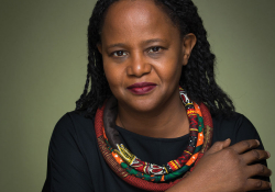 A photograph of Edwidge Danticat, wearing black offset by a colorful scarf, against an olive background