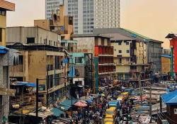 A photograph of a busy city street in Lagos with the skyline rising the background