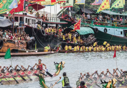 A photograph of a raucous public festival where teams of rowers in dragon boats traverse a river