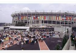 A crowd throngs into a stadium lined with flags from around the world