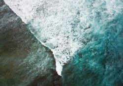 A turbulent wave, capped with foam, from above
