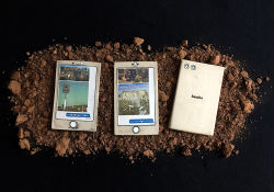 Three disheveled electronic tablets laying on a bed of soil. The third is turned face down
