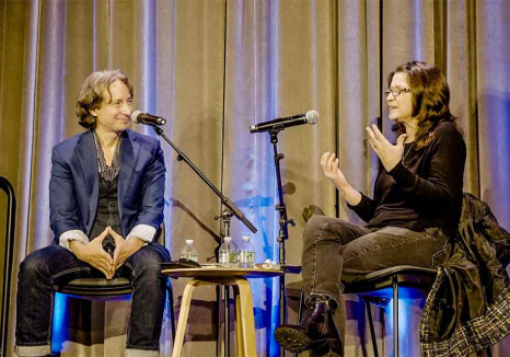 The interviewer and interviewee talk together on a stage